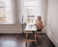 Blogger met hoofddoek werkt aan make-uplook bij raamlicht