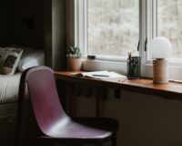 Rustige schrijfhoek met houten bureau, stoel en planten bij het raam