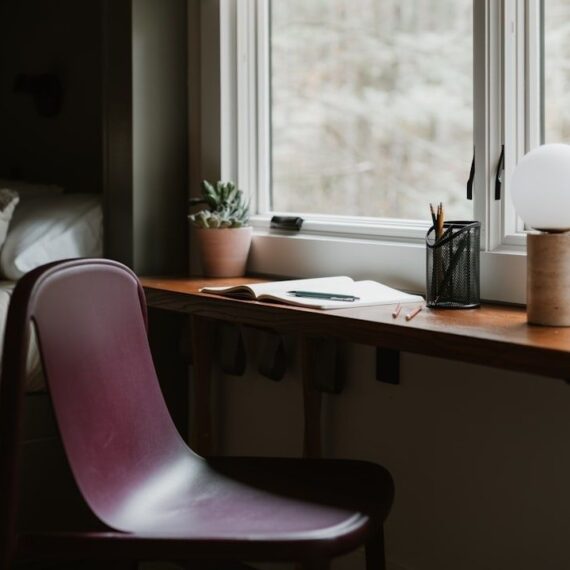 Rustige schrijfhoek met houten bureau, stoel en planten bij het raam