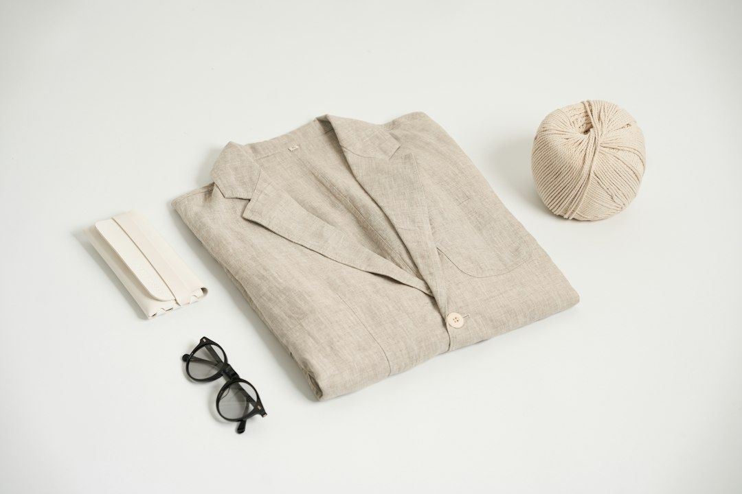 Opgevouwen zandkleurig linnen colbert met bril en accessoires