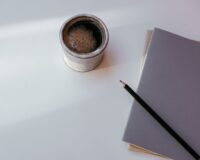 Kop koffie, notitieboek en potlood op een rustige ochtendtafel