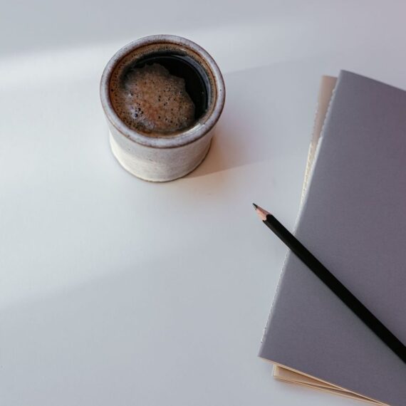 Kop koffie, notitieboek en potlood op een rustige ochtendtafel