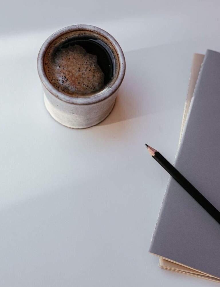 Kop koffie, notitieboek en potlood op een rustige ochtendtafel